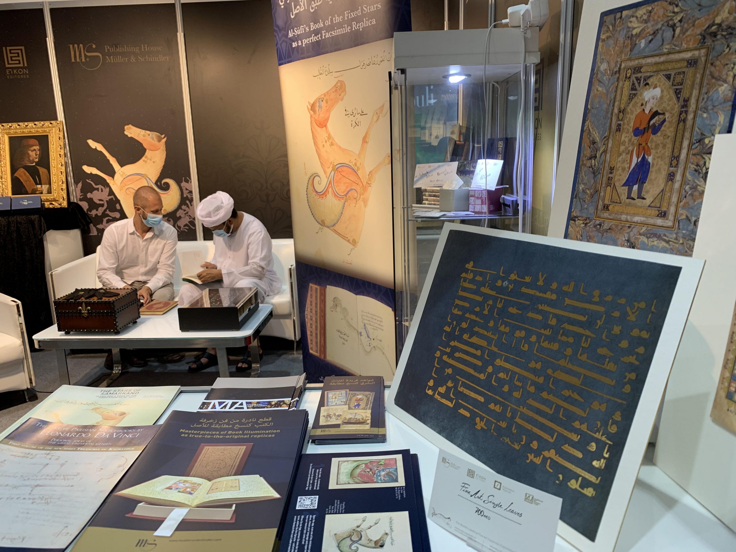 ADIBF22_j ADIBF 2022, unsere Messestand während der Buchmesse. Im Vordergrund unsere Prospekte sowie die Einzelfaksimileseite des Blauen Korans und des Jünglings mit Falke