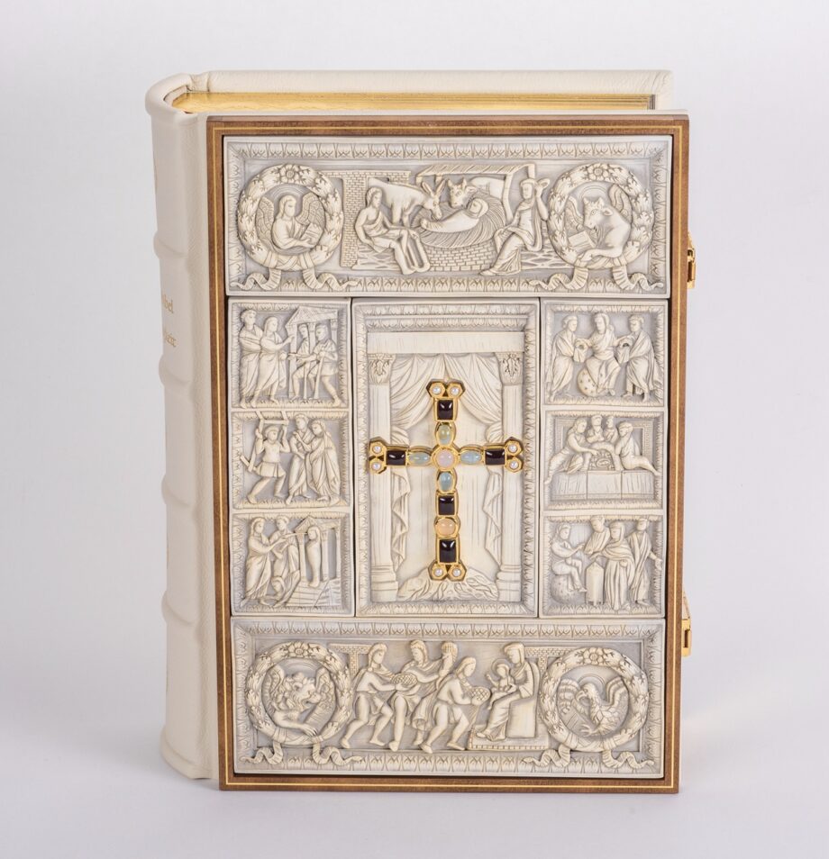 Bibel frontal: Einband mit Elfenbein-Replikaten in edlem Holzrahmen. In der Mitte des Einbands sieht man ein echtvergoldetes Prachtkreuz mit Edelsteinen besetzt.