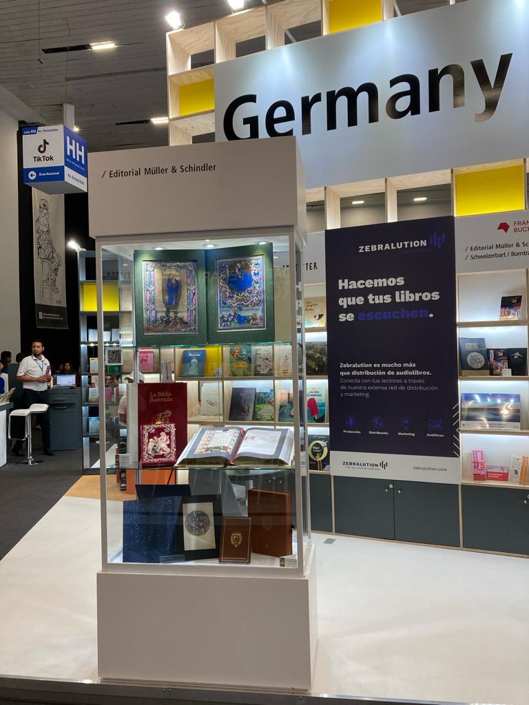 Glasvitrine am deutschen Gemeinschaftsstand mit Faksimile und edlen Einselzeiten aus unserem Verlagshaus. Rechts im Hintergrund ist "Germany" zu lesen.